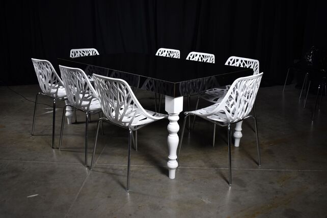 Black High Gloss White Legs Dining White Nest surrounded by eight intricately designed white chairs on a concrete floor.