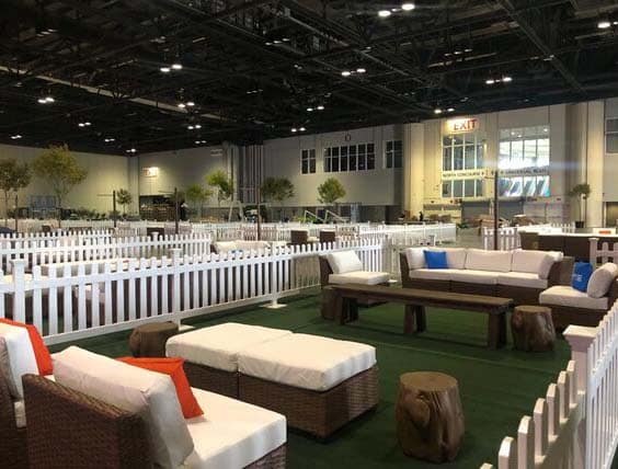 Spacious indoor lounge area with wicker sofas and white cushions, surrounded by white picket fencing