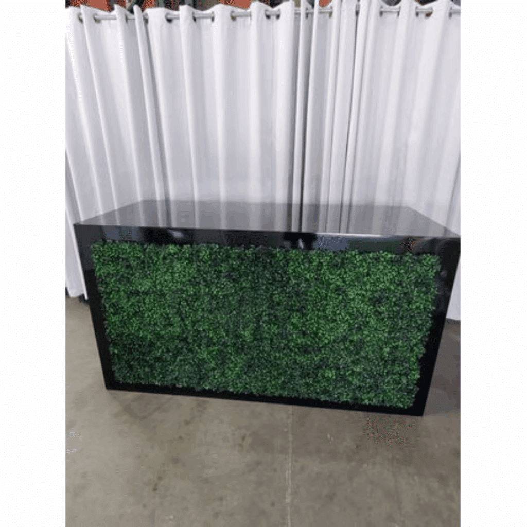 Boxwood Hedge Dividers counter with a green leafy front stands on a concrete floor. Behind it hangs a white curtain. The scene conveys a modern, organic feel.