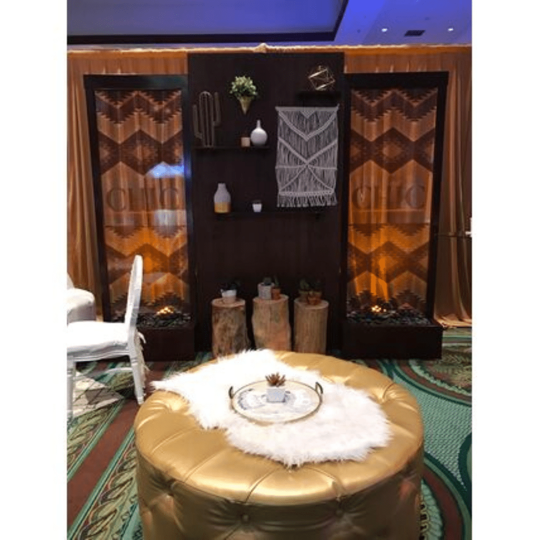 Stained Candle Wall lounge setup with a gold ottoman, white fur throw, and decorative tray.